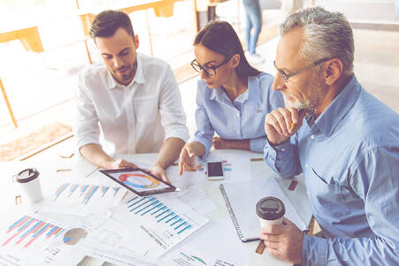 Mitarbeitende schauen sich gemeinsam ein Kreisdiagramm auf einem Tablet an